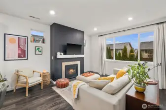 Living room with modern fireplace feature wall, floating mantel, recessed lighting, and large picture window overlooking the backyard and neighboring homes.