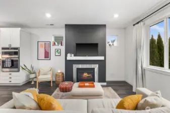 Front-facing view of the living area highlighting the fireplace focal point, open connection to the kitchen, recessed lighting, and wide plank-style flooring throughout the main living space.