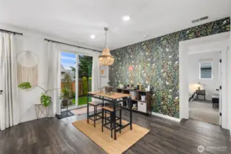 Dining area filled with natural light, featuring sliding glass door access to the backyard and a striking botanical accent wall that adds personality and warmth to the space.