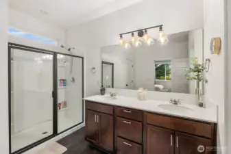 Bright primary bathroom featuring a spacious dual-sink vanity with large mirror, modern lighting, and a glass-enclosed shower. Clean lines and plenty of counter space create a calm, spa-like start to the day.