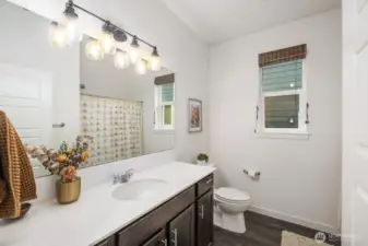 Well-appointed bathroom with single sink vanity, large mirror, overhead lighting, and a shower and tub combination. Natural light from the window helps keep the space feeling fresh and airy.