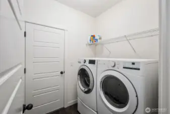 Dedicated laundry room with front-loading washer and dryer, overhead storage shelving, and convenient interior access for everyday household tasks.