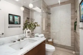 Secondary bathroom with custom vanity finished with walnut veneer, marble countertop, tiled floor and infinity shower drain.