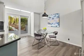 A charming kitchen dining space with room for a table, flowing effortlessly to a private deck and patio surrounded by lush, beautifully landscaped gardens.