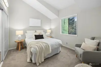 A bright second bedroom featuring a picture window that floods the space with natural light, complemented by a custom-designed closet for optimal storage.