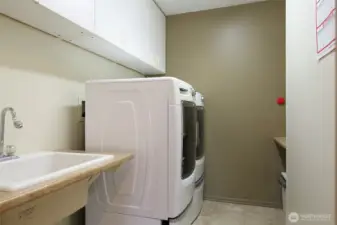Downstairs laundry with deep sink and plenty of cabinets and countertops