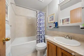 Upstairs guest bathroom with artistic tile surround that flows nicely into behind the toilet & sink! Soaking tub is oversized!