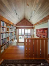 The upstairs hallway to the primary suite is lined with fir bookcases.