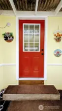 A cheerful pop of red sets the tone at this welcoming front entry, framed by sunny yellow siding that says “hello” before you even knock - hinting at the warmth and personality that awaits inside.