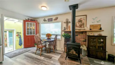 Gather around the fire and feel right at home in this enchanting nook, where rustic charm meets everyday comfort. Anchored by a cozy fireplace and surrounded by warm wood finishes, this sun-dappled dining area is perfect for slow breakfasts, heartfelt conversations, or winding down after a day by the coast.