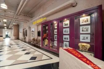 The Second-Floor Hallway Near the Elevator Features a Curated Museum Displaying Historical Artifacts from the Building's Past as a School