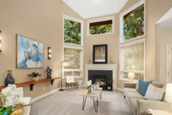 Stunning living room with soaring 16ft ceiling, floor to ceiling windows, and a cozy fireplace that provides added warmth.