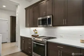 Upgraded cooktop and timeless full height backsplash.