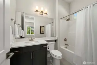 Sleek guest suite bathroom with Quartz counters and tiled flooring.