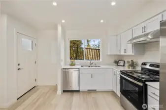 Functional kitchen layout with stainless appliances, modern cabinetry, and window views bringing in natural island light.