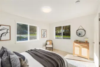 Upper-level bedroom with large window, natural light, and clean modern finishes consistent with new construction design.