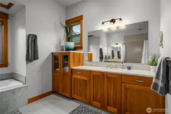 Spacious primary bathroom with dual vanities and tile flooring.