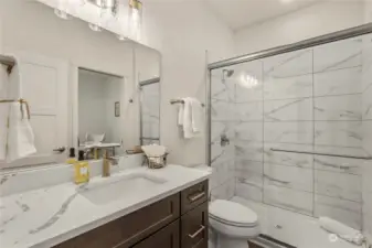 The Guest Bathroom boasts a sizable vanity with gorgeous quartz counters and a full tile shower with a sleek sliding glass door.