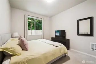 Primary bedroom looks out to private backyard and many trees.