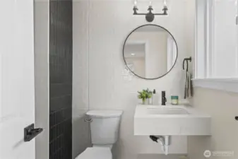 Sink, commode and entry to shower off the primary!  Adorned with tile work and custom trim.