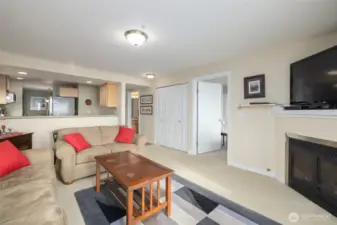 The living room, looking toward primary suite (open door, right of center), laundry closet (two closed closet doors), kitchen, and guest bath (open door, left of center).