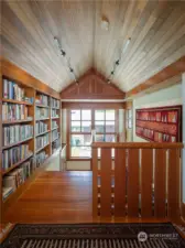 The hallway upstairs to the primary suite is lined with built-in fir bookcases.