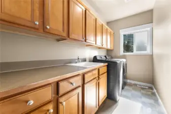 Extremely generous laundry room with an abundance of cabinets, counterspace and a sink!