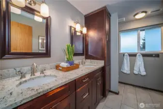 The updated full hall bath offers double vanities, ample storage, granite countertops, and tile floors.
