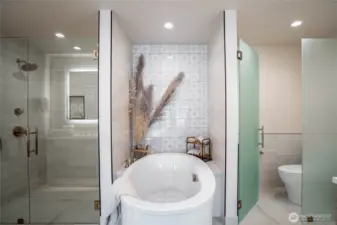 Modern jetted self-cleaning soaking tub is the focal point of the en suite primary bathroom.