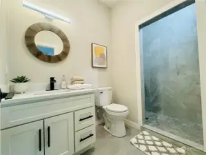 spacious bathroom with wall to ceiling tiled shower