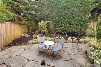 Surrounded by lush greenery and freshly planted flower beds, this peaceful backyard retreat invites quiet moments and casual gatherings alike. Lovely water feature in back left corner.