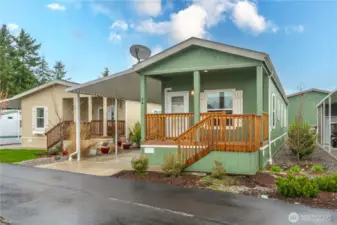 Like-new manufactured home with a fresh, modern design, charming front porch, and well-maintained landscaping.