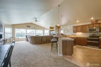 But first, stepping forward past the dining table, the kitchen and living room have expansive water views, and also access to the covered rear deck.