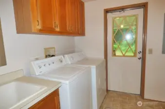 Laundry room with cabinets, sink,washer and dryer (included). Door leads to covered deck.