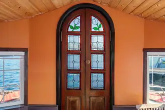 Through the living room, arrive at a beautifully designed set of stained glass double doors that lead out onto the back deck.
