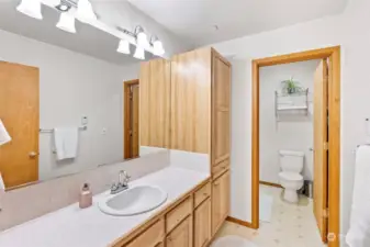 Well lit attached primary bathroom with expansive vanity and storage, plus toilet and shower room.