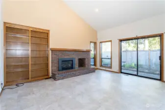 Family room with built-in bookshelves, brick surrounded fireplace with natural gas insert, slider to rear patio and garden