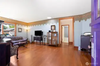 Light-filled living room showcases original hardwood floors, beautiful custom baseboards, and timeless architectural charm.