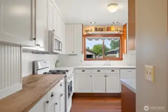 Warm butcher block counters and tall cupboards offer beauty and function in this inviting kitchen.