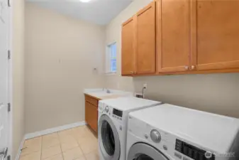 Laundry room with upgraded cabinets, sink, and tile floors.