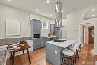 Kitchen features quartz counters, island with breakfast bar and tons of cabinets. There is also a built in bench for a full size kitchen table