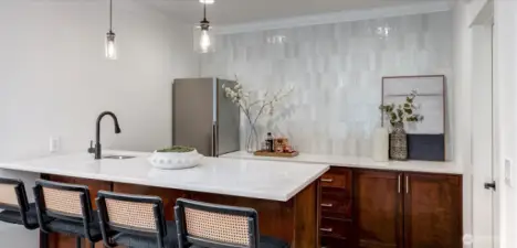 Exquisite full bar is the heart of the lower level! Stunning light and bright quartzite counters create a striking focal point, while curated tiling adds a touch refinement.