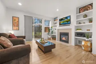 Light-filled open layout living space with large windows and cozy fireplace, designed for comfortable everyday living and easy entertaining.