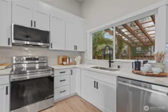 Crisp white cabinetry, quartz counters, tile backsplash, and backyard views create a clean, move-in-ready space.