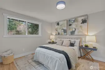 Peaceful primary bedroom with hardwood floors and serene light filled partial views.
