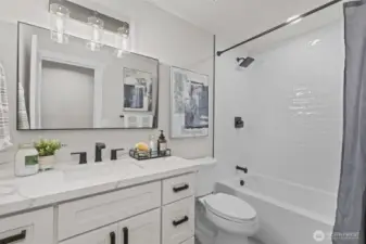Remodeled full bath with quartz vanity, subway tile surround, and modern black fixtures for a fresh, contemporary feel.