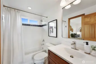 Bright and cheery ensuite bath off of the primary bedroom is also connected to the hallway for guests.