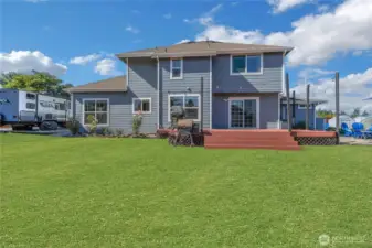 Back of the home includes deck, RV parking and gravel patio. Grass is enhanced