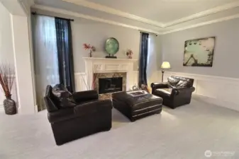 Formal Living room with gas fireplace, wood mantle and marble tiles surrounding it. Crown & Cove Molding and Wainscoting decorate this comfortable room.
