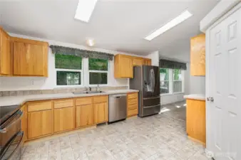 The kitchen features stainless steel appliances, warm-toned cabinetry, ample counter space, abundant storage, and a walk-in pantry.